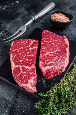 Taze çiğ Denver bifteği, mermer et ve şifalı otlar. Siyah arka plan. Üst görünüm