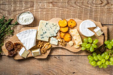 Peynirli peynirli, peynirli, peynirli, rokforlu, parmesanlı, üzümlü, incirli, ekmekli ve fındıklı krem peynirli. Ahşap arka plan. Üst görünüm
