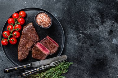 Kızarmış Denver bifteği ve kekik tabağı. Siyah arka plan. Üst Manzara. Boşluğu kopyala