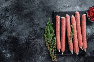 Mermer tahtada kekik olan taze çiğ sosis kasapları. Siyah arka plan. Üst Manzara. Boşluğu kopyala