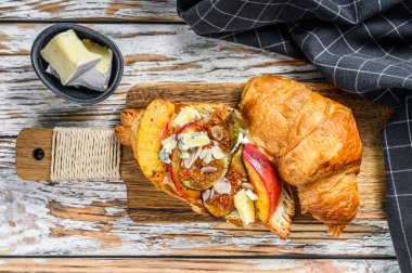 Krem peynirli, şeftalili ve incirli taze kruvasan sandviçi. Nefis bir kahvaltı. Beyaz arka plan. Üst görünüm