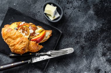 Krem peynirli, şeftalili ve incirli taze kruvasan sandviçi. Nefis bir kahvaltı. Siyah arka plan. Üst Manzara. Boşluğu kopyala