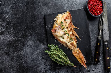 Kesme tahtasında ızgara Kızıl Deniz levreği. Siyah arka plan. Üst Manzara. Boşluğu kopyala