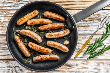 Tavada kızartılmış ev yapımı sosisler, biftek ve domuz eti. Ahşap arka plan. Üst görünüm