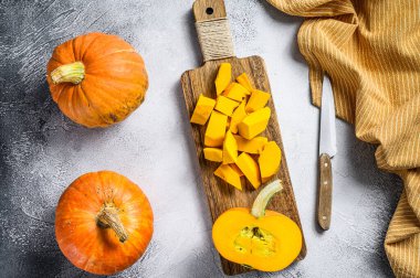 Kesme tahtasındaki çiğ balkabağı küpleri. Beyaz arka plan. Üst görünüm