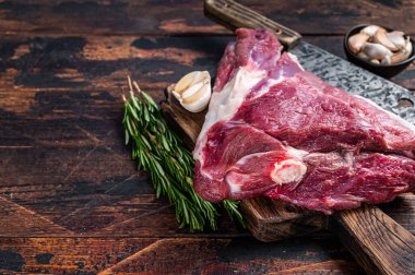 Et satırıyla kasap panosunda pişmemiş çiğ koyun budu. Koyu ahşap arka plan. Üst Manzara. Boşluğu kopyala