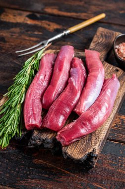 Çiğ kuzu fileto fileto, ahşap tahtada koyun filetosu otlu et. Koyu ahşap arka plan. Üst görünüm