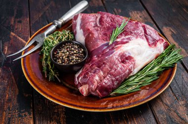 Pişmemiş çiğ keçi budu ya da biberiyeli bacak ve kekik kırsal tabakta. Koyu ahşap arka plan. Üst Manzara. Boşluğu kopyala