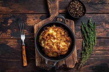 Kızarmış patates gözlemesi ya da tavada otlu börek. Koyu ahşap arka plan. Üst görünüm