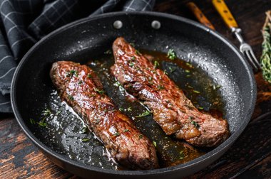 Tavada ızgara etekli pala bifteği. Koyu ahşap arka plan. Üst görünüm