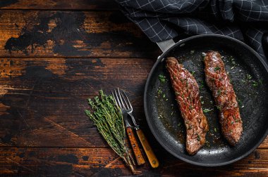 Tavada ızgara etekli pala bifteği. Koyu ahşap arka plan. Üst Manzara. Boşluğu kopyala