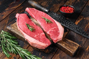 Kesme tahtasında çiğ sığır eti sığır filetosu bifteği. Koyu ahşap arka plan. Üst görünüm