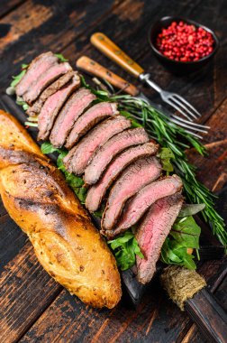 Biftekli baget sandviç ve yanında roka. Koyu ahşap arka plan. Üst görünüm