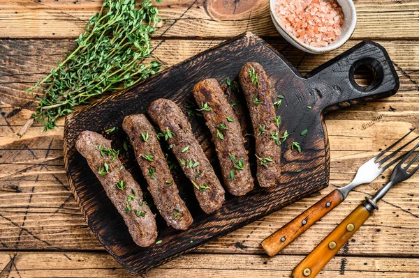 Homamade grelhou salsichas de carne de kebab Lula em uma tábua de corte. fundo de madeira. Vista superior — Fotografia de Stock