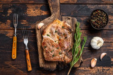 Kesme tahtasının üzerinde domuz pirzolası. Koyu ahşap arka plan. Üst görünüm