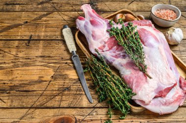 Tahta tepside çiğ keçi budu eti. Ahşap arka plan. Üst Manzara. Boşluğu kopyala