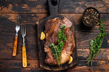 Kesme tahtasının üzerinde ızgara Chuck 'ın gözleme bifteği. Koyu ahşap arka plan. Üst görünüm