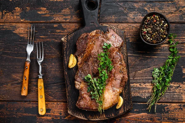 Kesme tahtasının üzerinde ızgara Chuck 'ın gözleme bifteği. Koyu ahşap arka plan. Üst görünüm