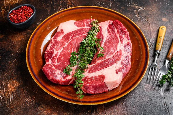 Raw Chuck eye roll steaks organic beef meat. Dark background. Top view