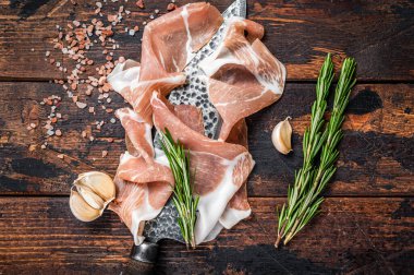 Kasap bıçağında kurutulmuş jambonlu jambon. Koyu ahşap arka plan. Üst Görünüm