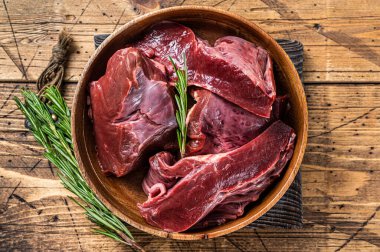 Dilimlenmiş sığır eti ya da ahşap bir tabakta otlu çiğ kalp. Ahşap arka plan. Üst Görünüm