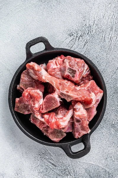 Raw diced meat cubes with bone in a pan. White background. Top View