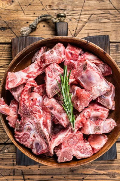 Carne cruda fresca sull'osso tagliata a dadini per il gulasch in un piatto di legno. Sfondo in legno. Vista dall'alto — Foto Stock