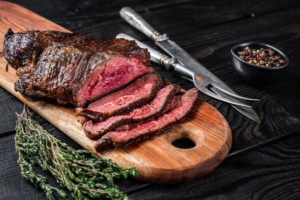 Grillade slaktare väljer biff Onglet Hanging Tender nötkött kött på en skärbräda. Svart trä bakgrund. Ovanifrån — Stockfoto