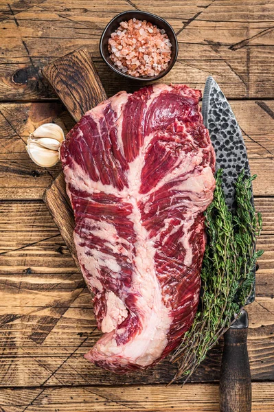 Onglet nebo oběsit syrový hovězí steak na řeznické desce s nožem. dřevěné pozadí. Pohled nahoru — Stock fotografie