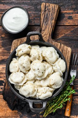 Pelmeni usulü Rus böreği, biftek ve domuz eti. Koyu ahşap arka plan. en üstteki görünüm