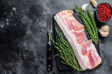 Çiğ domuz pastırması pişirmeye hazır. Siyah arka plan. Üst Manzara. Boşluğu kopyala