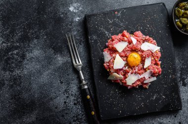 Bıldırcın yumurtası, kapari ve parmesan peynirli Tatar bifteği. Siyah arka plan. Üst Manzara. Boşluğu kopyala