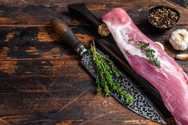 Çiğ domuz filetosu eti ve satırla birlikte kürek tahtasının üzerinde. Koyu ahşap arka plan. Üst Manzara. Boşluğu kopyala