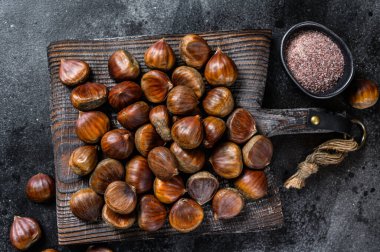 Tahta kesme tahtasında çiğ kestane. Siyah arka plan. Üst görünüm