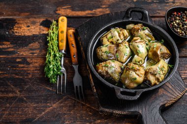 Tavada zeytinyağında marine edilmiş enginar. Koyu ahşap arka plan. Üst Manzara. Boşluğu kopyala