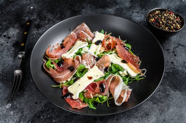 Peynirli peynirli jambonlu jambonlu jambon salatası ve roka. Siyah arka plan. Üst görünüm