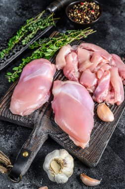 Tahta bir kesme tahtasının üzerinde dilimlenmiş çiğ tavuk filetosu. Siyah arka plan. Üst görünüm