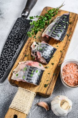 Tahta kesme tahtasının üzerinde dilimlenmiş tuzlu uskumru balığı. Beyaz arka plan. Üst görünüm