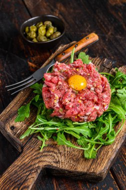 Bıldırcın yumurtalı ve roka dilimlenmiş tart bifteği. Koyu ahşap arka plan. Üst görünüm