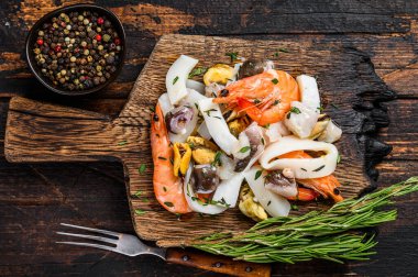 Çiğ deniz ürünleri kokteyli karides, karides, midye, mürekkep balığı ve ahtapotla karıştırılmış. Koyu ahşap arka plan. Üst görünüm