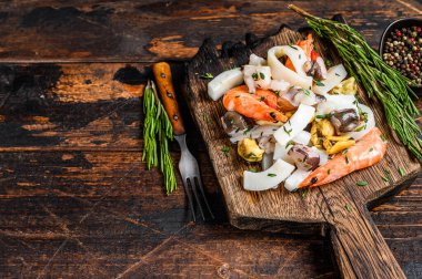 Çiğ deniz ürünleri kokteyli karides, karides, midye, mürekkep balığı ve ahtapotla karıştırılmış. Koyu ahşap arka plan. Üst Manzara. Boşluğu kopyala