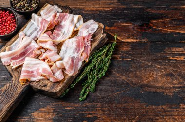 Tahta kesme tahtasında çiğ domuz pastırması dilimleri. Koyu ahşap arka plan. Üst Manzara. Boşluğu kopyala