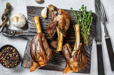 Ahşap kesme tahtasının üzerinde ağır ateşte kızartılmış kuzu Shanks. Beyaz arka plan. Üst görünüm