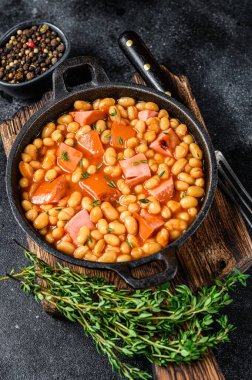 Tavada füme sosis ve domates soslu haşlanmış böbrek fasulyesi. Siyah arka plan. Üst Manzara. Boşluğu kopyala