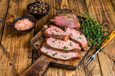 Ahşap kesme tahtasının üzerinde az pişmiş sığır eti fileto bifteği. Ahşap arka plan. Üst görünüm