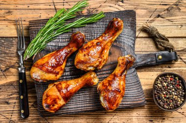 Ahşap kesme tahtasının üzerinde ızgara kızarmış tavuk budu. Ahşap arka plan. en üstteki görünüm