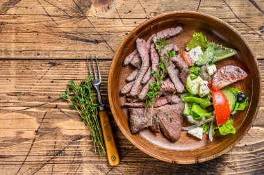 Ahşap tabakta biftek ve sebze salatası ile sığır eti pirzolası. Ahşap arka plan. Üst Manzara. Boşluğu kopyala