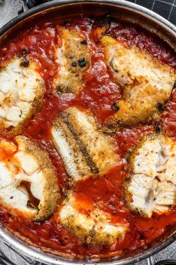 Fırında pişirilmiş makrozor beyaz balığı ve tavada domates. Beyaz tahta arka plan. Üst görünüm