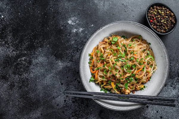 Wok Hot Asian cellophane noodles with chicken meat. Black background. Top view. Copy space