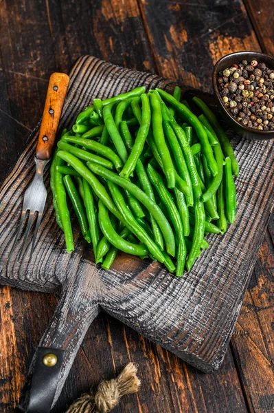 Verse groene bonen op een snijplank. Donker houten achtergrond. bovenaanzicht — Stockfoto